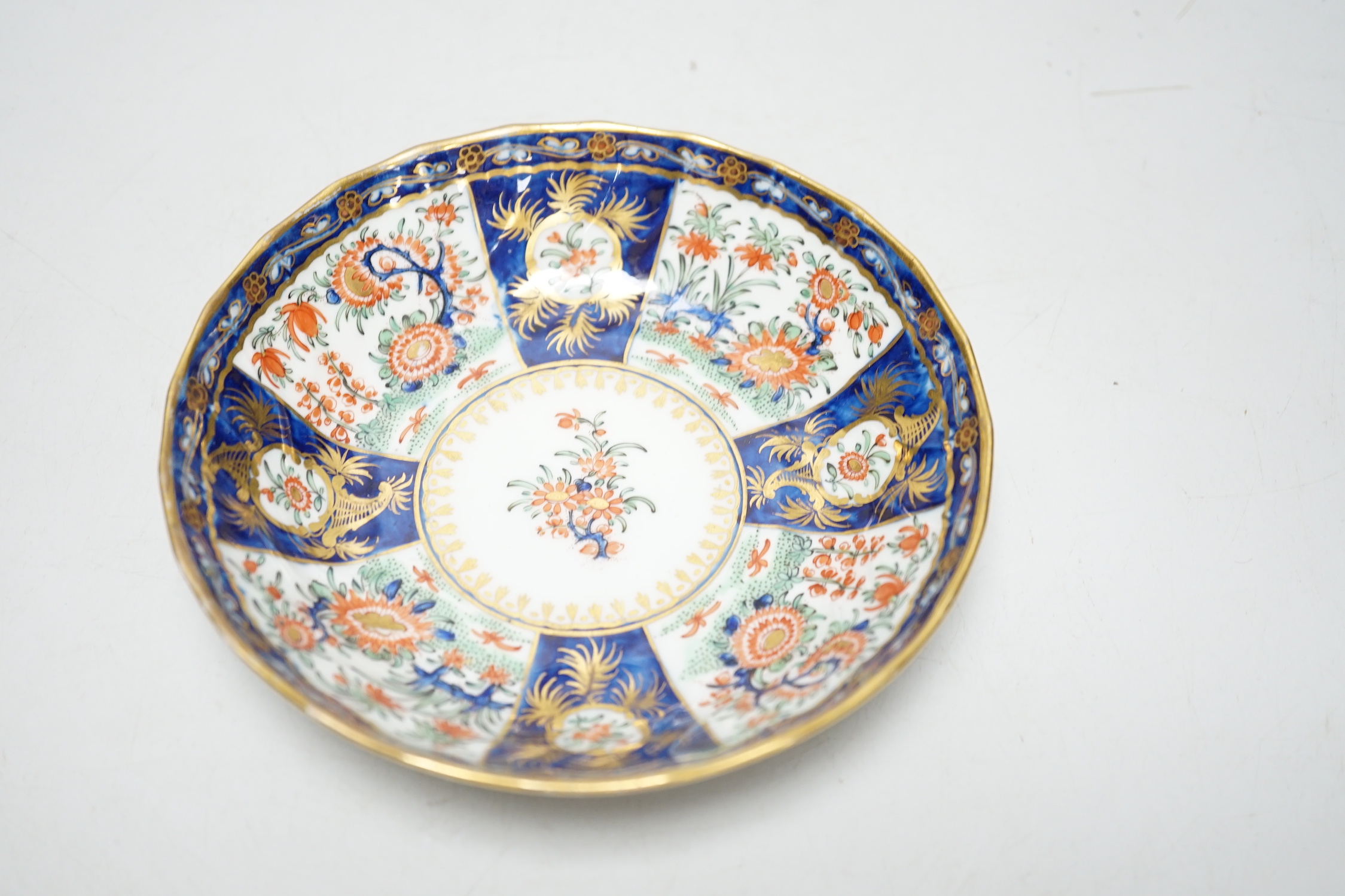 A Chamberlains Worcester good kakiemon style teabowl and saucer painted with oriental flowering plants in fan shaped panel, c.1785-90